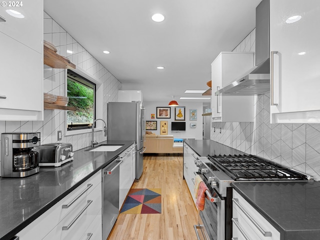 kitchen with stainless steel appliances, white cabinetry, light hardwood / wood-style floors, and sink