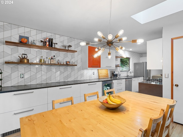 kitchen with white cabinetry, wine cooler, backsplash, light hardwood / wood-style flooring, and a skylight