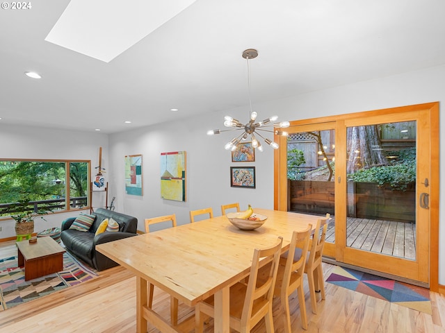 dining area featuring light wood-type flooring, a skylight, and a notable chandelier