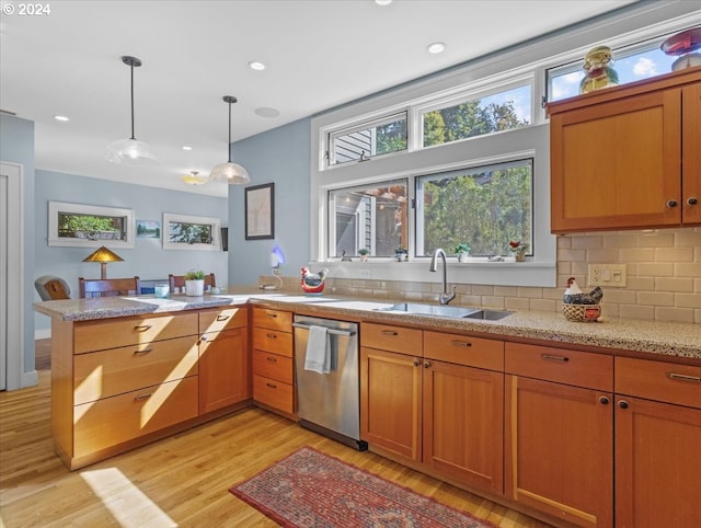 kitchen featuring decorative light fixtures, sink, decorative backsplash, stainless steel dishwasher, and light hardwood / wood-style floors