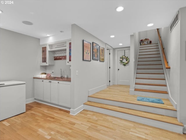 foyer entrance with light wood-type flooring and wet bar