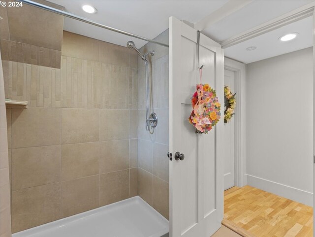 bathroom featuring tiled shower and wood-type flooring