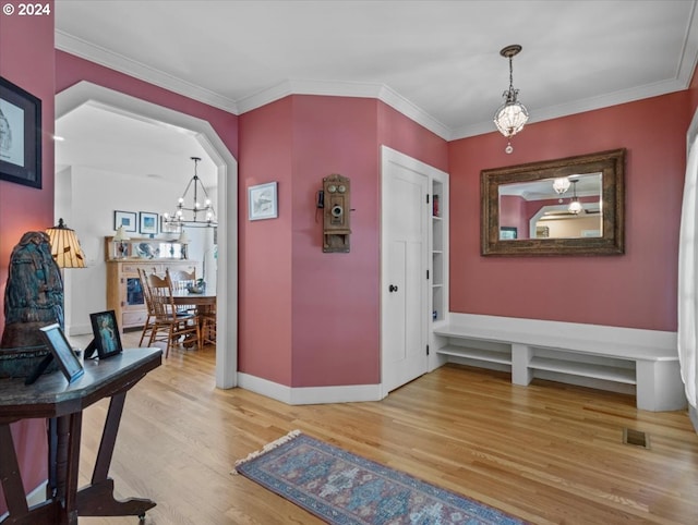 entrance foyer with crown molding, light hardwood / wood-style flooring, and a chandelier