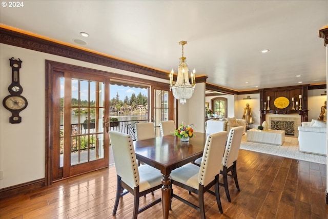 dining space with a fireplace, ornamental molding, a chandelier, and wood-type flooring