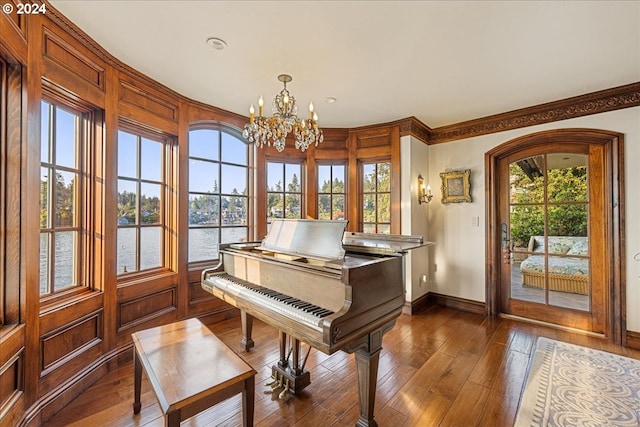 misc room featuring a water view, a healthy amount of sunlight, dark hardwood / wood-style flooring, and an inviting chandelier