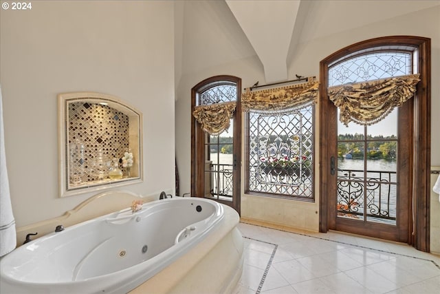 bathroom with tile patterned flooring, a washtub, high vaulted ceiling, and a water view