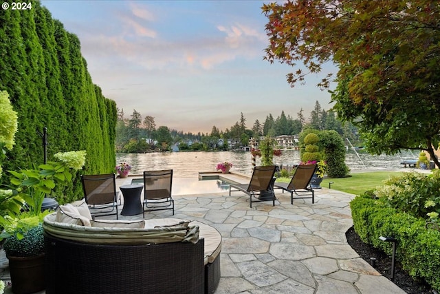 patio terrace at dusk featuring a water view