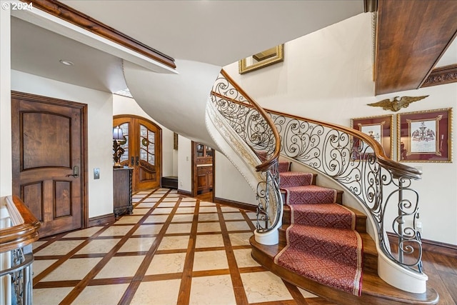 entryway featuring stairs, baseboards, arched walkways, and french doors