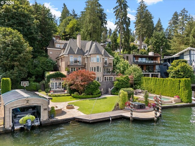 rear view of property featuring a balcony, a yard, and a water view