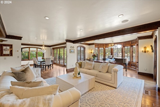 living room featuring a wealth of natural light, ornamental molding, an inviting chandelier, and light wood-type flooring