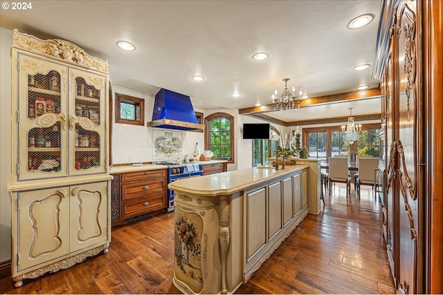 kitchen featuring stainless steel range, light countertops, custom range hood, an inviting chandelier, and a kitchen island