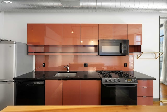 kitchen with black appliances, sink, and dark stone counters