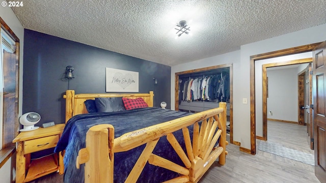 bedroom featuring a closet, a textured ceiling, baseboards, and wood finished floors