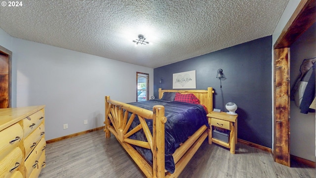 bedroom featuring a textured ceiling, wood finished floors, and baseboards