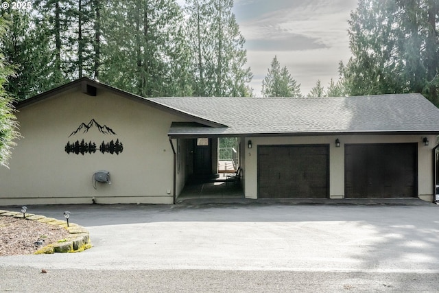 ranch-style house with an attached garage, stucco siding, driveway, and roof with shingles