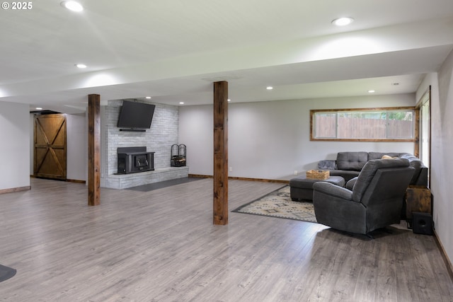 living area with recessed lighting, a brick fireplace, baseboards, and wood finished floors