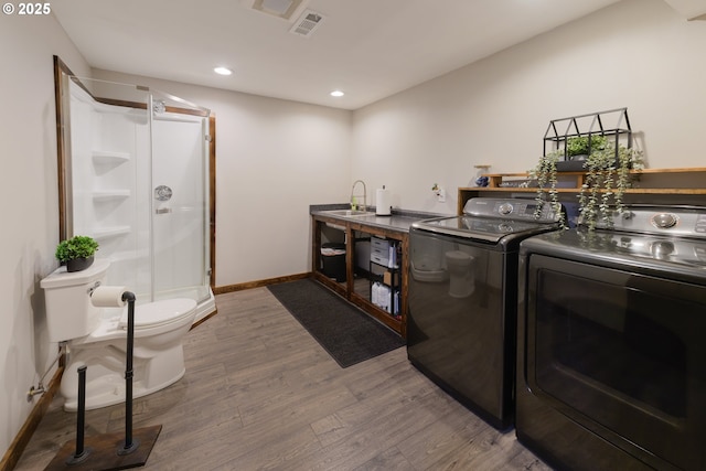 clothes washing area featuring recessed lighting, wood finished floors, washer and dryer, laundry area, and baseboards