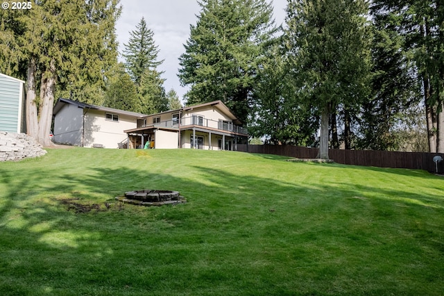 view of yard with a deck, an outdoor fire pit, and fence