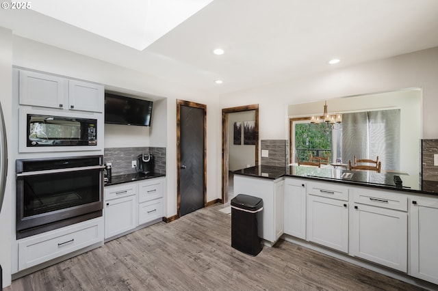 kitchen with dark countertops, black microwave, oven, and light wood-style flooring