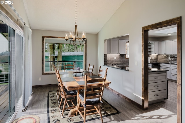 dining room featuring lofted ceiling, a notable chandelier, baseboards, and wood finished floors