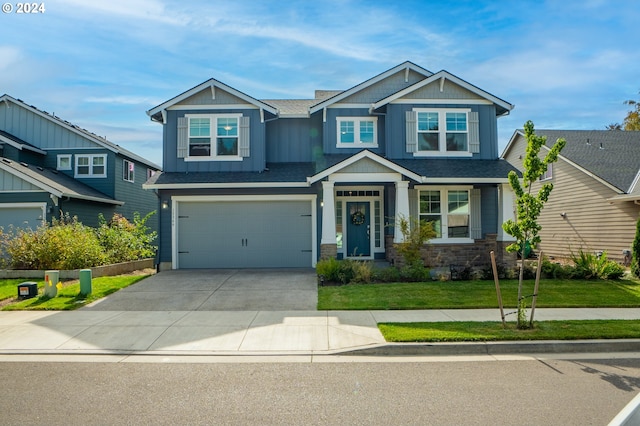 craftsman-style home featuring board and batten siding, a front lawn, driveway, stone siding, and an attached garage