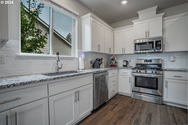 kitchen with white cabinets, appliances with stainless steel finishes, dark hardwood / wood-style floors, and sink