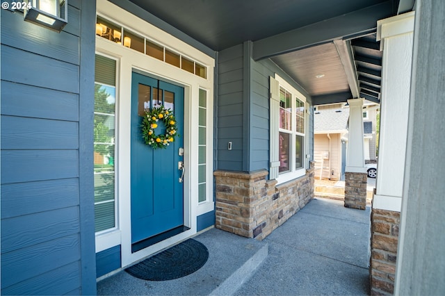 doorway to property with stone siding and covered porch