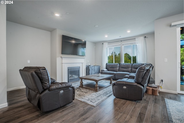 living area featuring recessed lighting, baseboards, dark wood-type flooring, and a glass covered fireplace