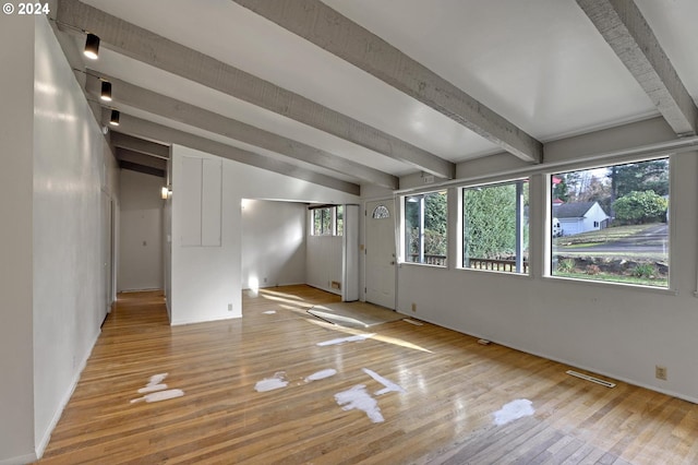 empty room with beamed ceiling and light hardwood / wood-style floors