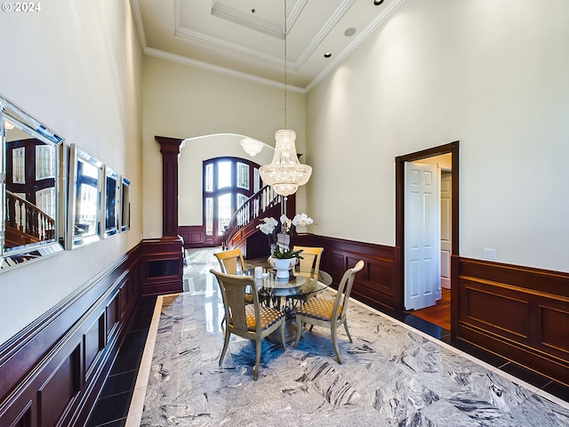 dining space featuring ornamental molding, ornate columns, a towering ceiling, and a notable chandelier