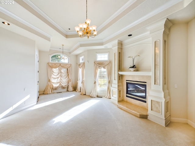 unfurnished living room featuring a raised ceiling, light colored carpet, a premium fireplace, crown molding, and a notable chandelier