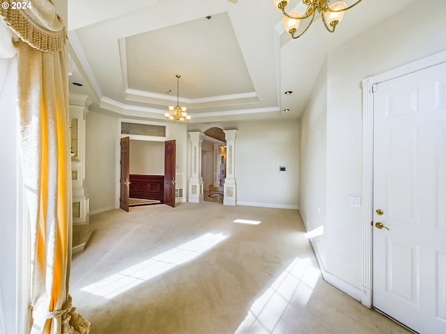 interior space featuring an inviting chandelier, crown molding, light colored carpet, decorative columns, and a tray ceiling