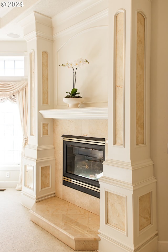 interior details featuring ornamental molding, a premium fireplace, and carpet flooring