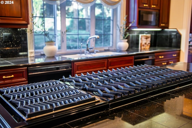 kitchen with tasteful backsplash, dishwasher, dark countertops, black microwave, and a sink