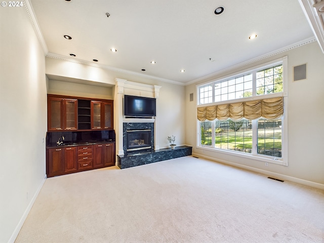 unfurnished living room featuring crown molding, baseboards, a high end fireplace, and light colored carpet