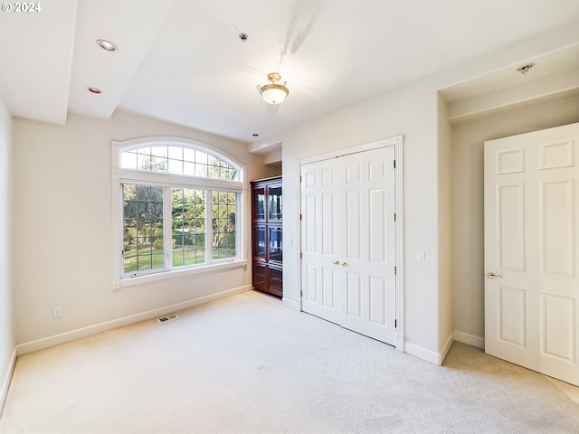 unfurnished bedroom with a closet and light carpet