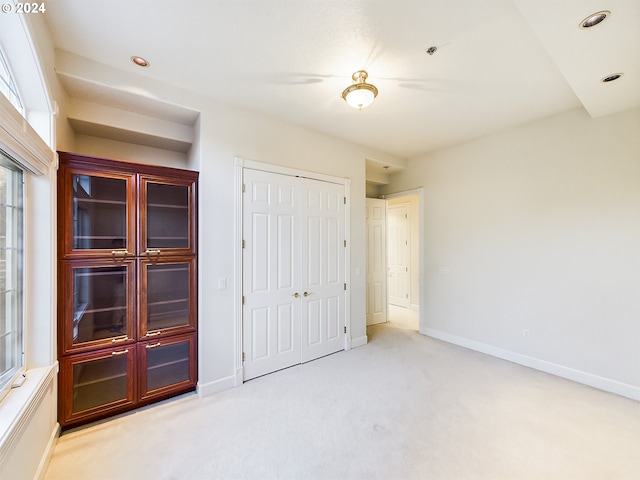 unfurnished bedroom with light carpet and a closet