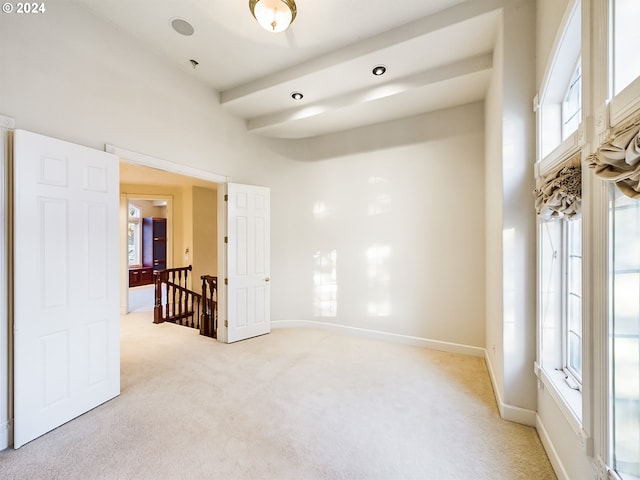 empty room featuring light carpet, a towering ceiling, and baseboards