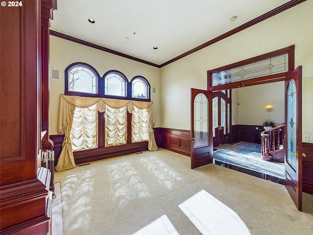 carpeted bedroom with ornamental molding and wainscoting