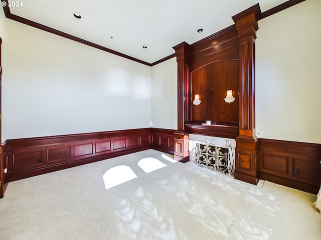 empty room featuring ornate columns, carpet, ornamental molding, and wainscoting