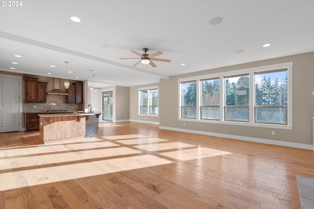 unfurnished living room featuring light hardwood / wood-style floors, ceiling fan, and sink