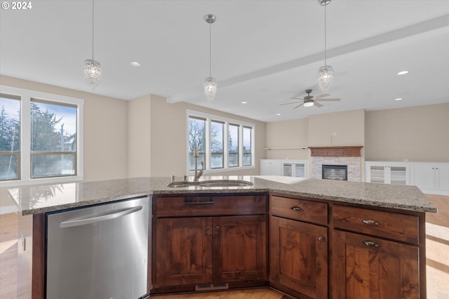 kitchen featuring stainless steel dishwasher, ceiling fan, a fireplace, a center island, and light hardwood / wood-style floors