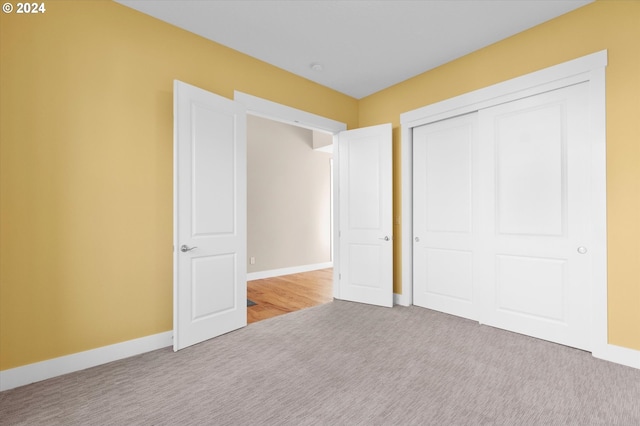 unfurnished bedroom with a closet and light colored carpet