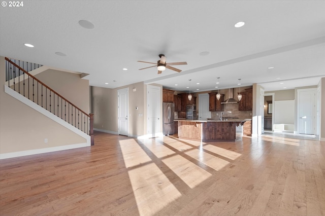 unfurnished living room with ceiling fan, sink, and light hardwood / wood-style floors