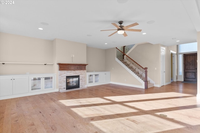 unfurnished living room with ceiling fan, light hardwood / wood-style floors, and a fireplace