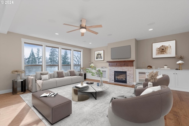 living room featuring a fireplace, ceiling fan, and light hardwood / wood-style flooring