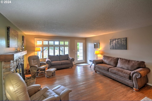 living room with a textured ceiling, a fireplace, and hardwood / wood-style floors