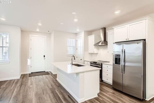 kitchen with white cabinetry, sink, wall chimney exhaust hood, an island with sink, and appliances with stainless steel finishes