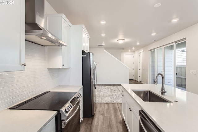 kitchen with white cabinets, sink, stainless steel appliances, and wall chimney range hood