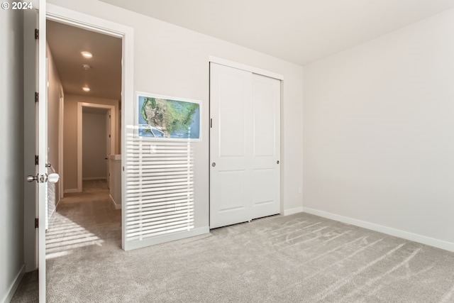 unfurnished bedroom featuring light carpet and a closet